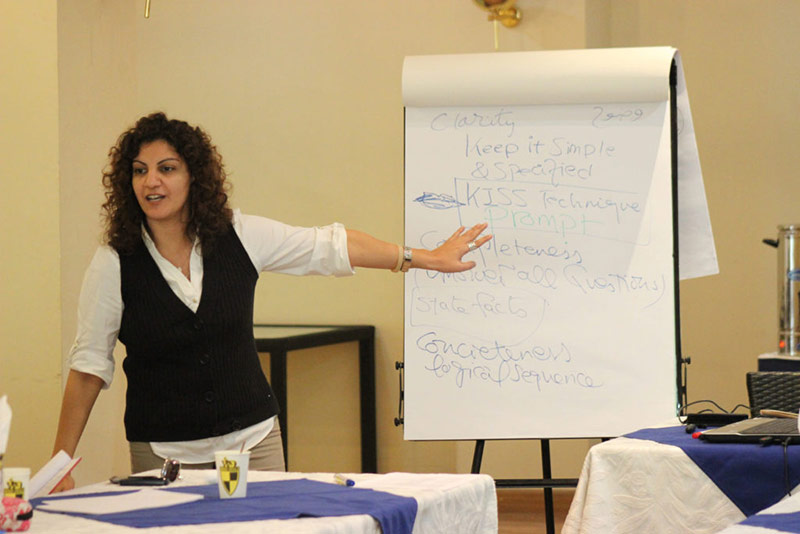 A trainer is pointing at the flip chart which indicates corporate training